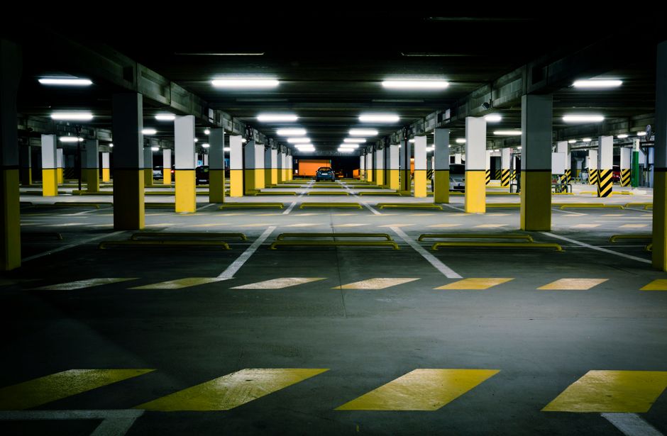 View of a modern underground parking garage with bright lighting and empty parking spaces.